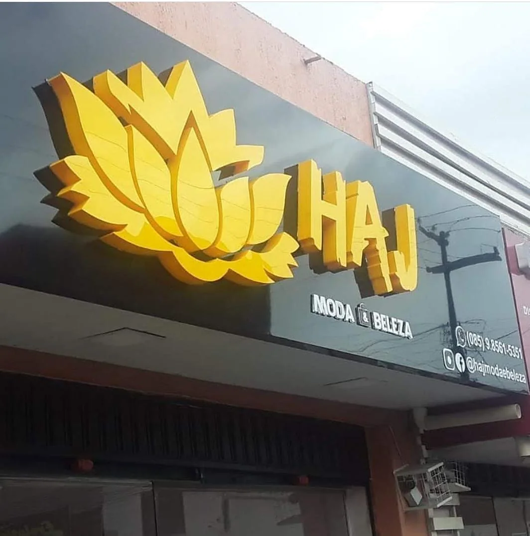 Símbolo e letras douradas em fachada. Fotografia de trabalho da VLT Acrílicos.