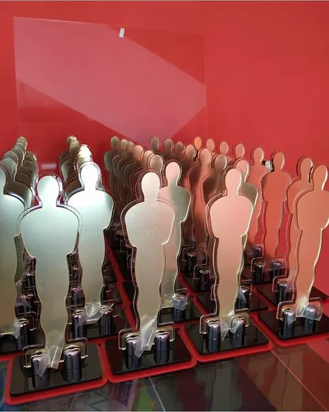 Troféus com figuras em acabamento dourado. Fotografia de trabalho da VLT Acrílicos.