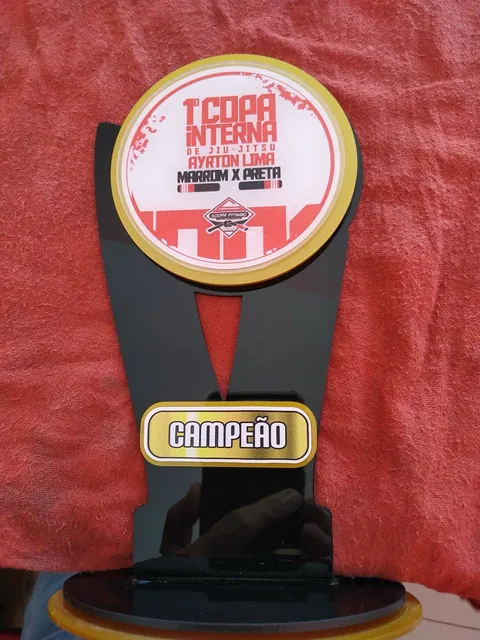 Troféu de futebol em vermelho e amarelo. Fotografia de trabalho da VLT Acrílicos.