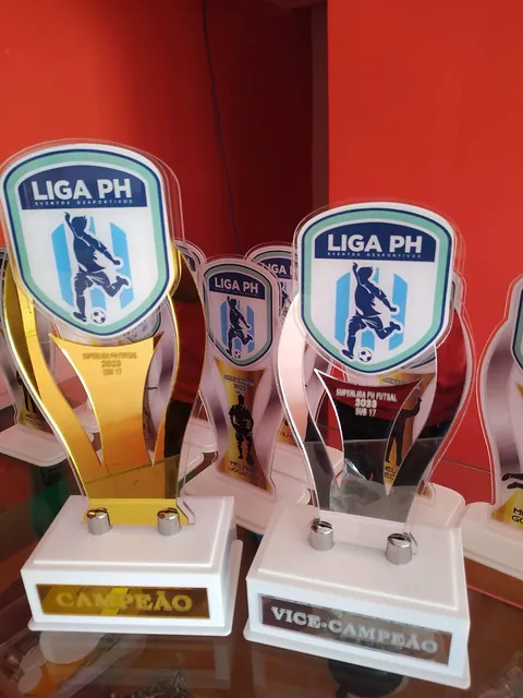 Troféus Liga PH em branco e dourado. Fotografia de trabalho da VLT Acrílicos.