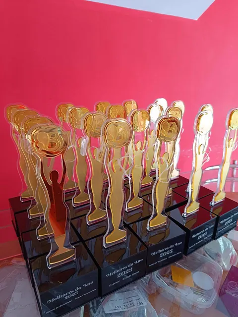 Conjunto de troféus com figuras douradas. Fotografia de trabalho da VLT Acrílicos.